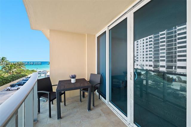 A balcony with a small table and two chairs overlooks the ocean and parking lot — 2501 S Ocean Dr # 402, Hollywood FL 33019, HOLLYWOOD, FL