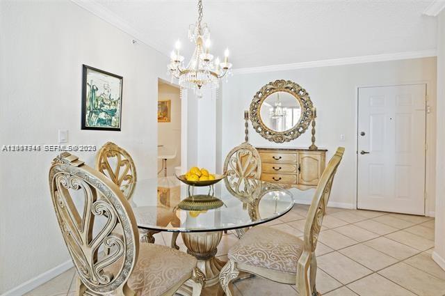 A dining room features a glass-topped table, ornate chairs, a chandelier, and a round mirror — 2501 S Ocean Dr # 402, Hollywood FL 33019, HOLLYWOOD, FL