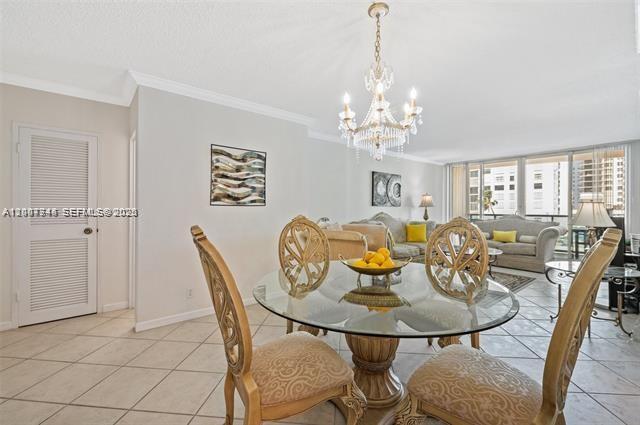 A dining area with a glass table and chandelier sits before a living room space — 2501 S Ocean Dr # 402, Hollywood FL 33019, HOLLYWOOD, FL