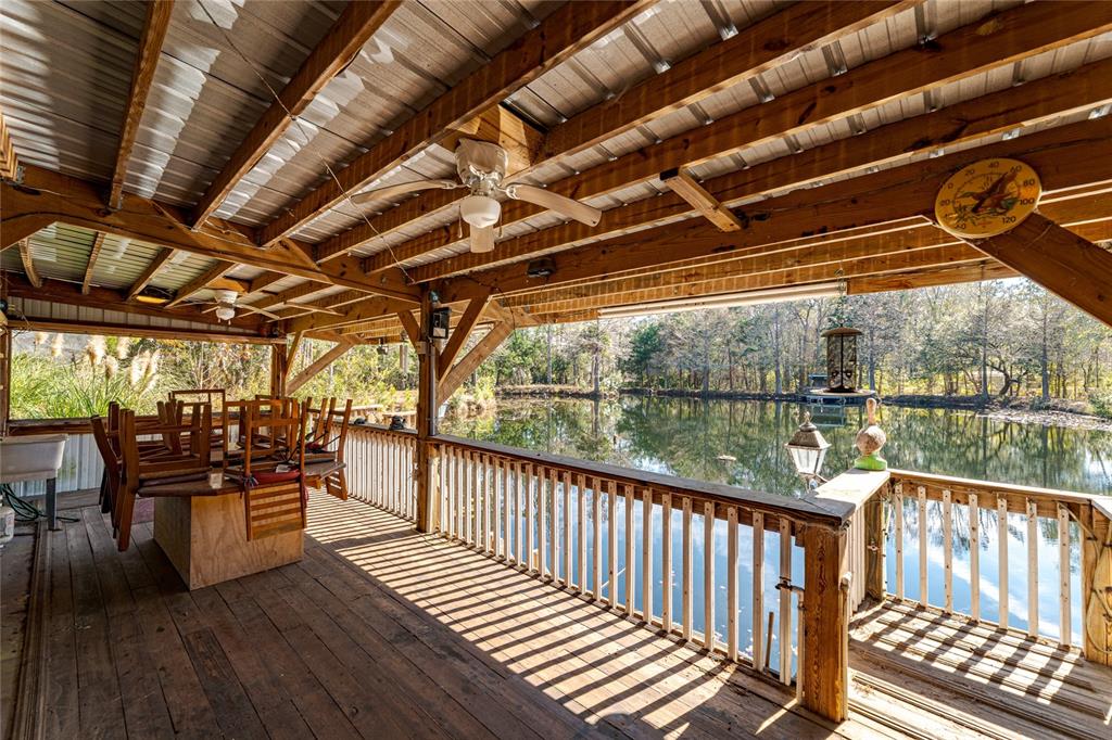 A covered wooden deck overlooks a pond with a railing and outdoor ceiling fans — 11053 MULBERRY LANDING ANNEX, HILLIARD, FL