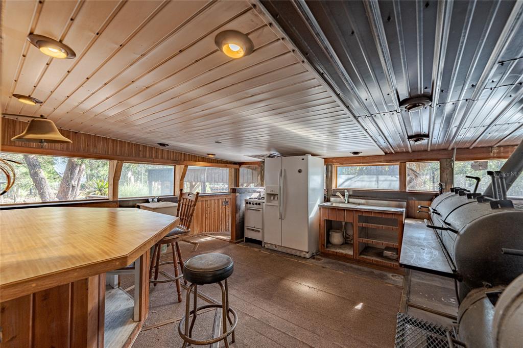 A rustic outdoor kitchen features a large smoker, a refrigerator, a stove, and wooden paneling — 11053 MULBERRY LANDING ANNEX, HILLIARD, FL