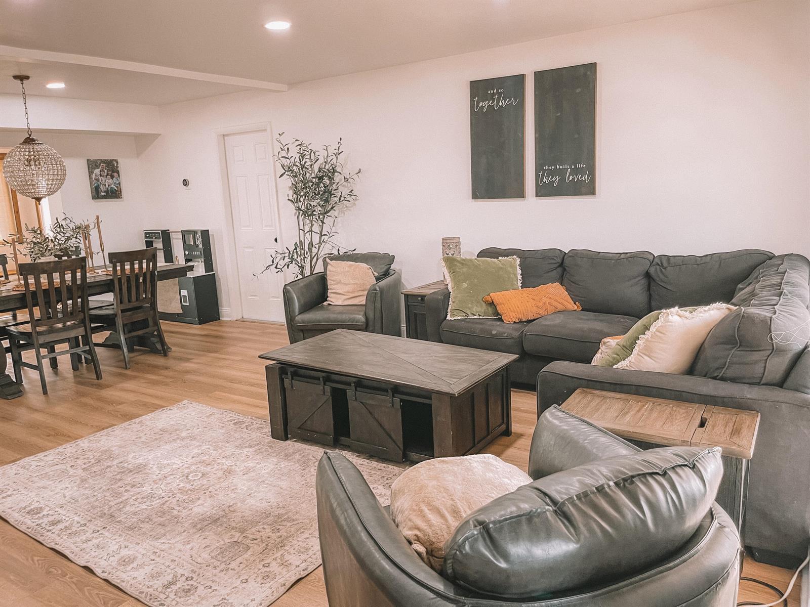 A living room with dark leather furniture, a coffee table, and wall art on wood floors — 2171 NE 44th Court, Lighthouse Point FL 33064, LIGHTHOUSE POINT, FL