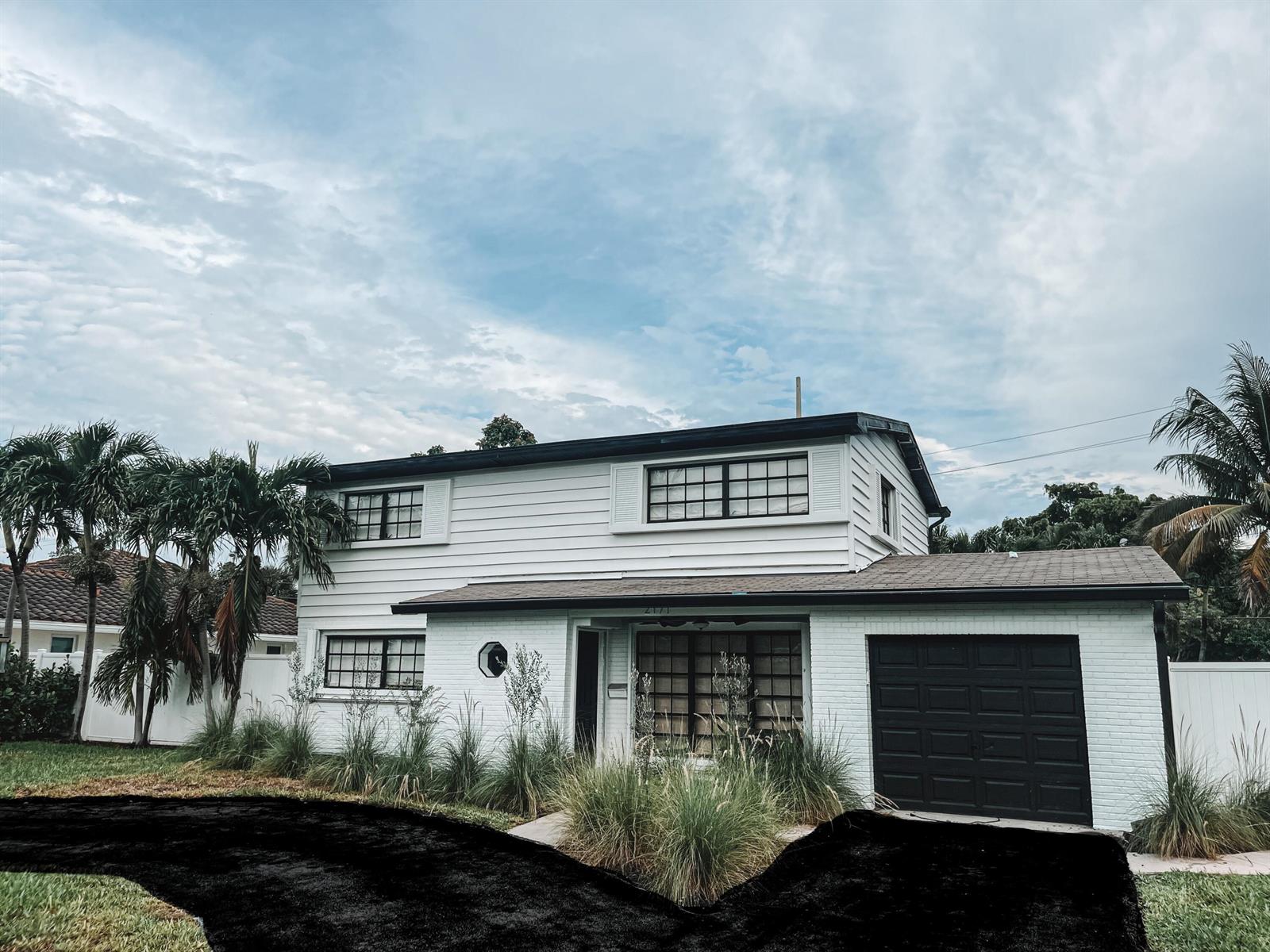 A two-story white house with a black garage door and a black driveway — 2171 NE 44th Court, Lighthouse Point FL 33064, LIGHTHOUSE POINT, FL