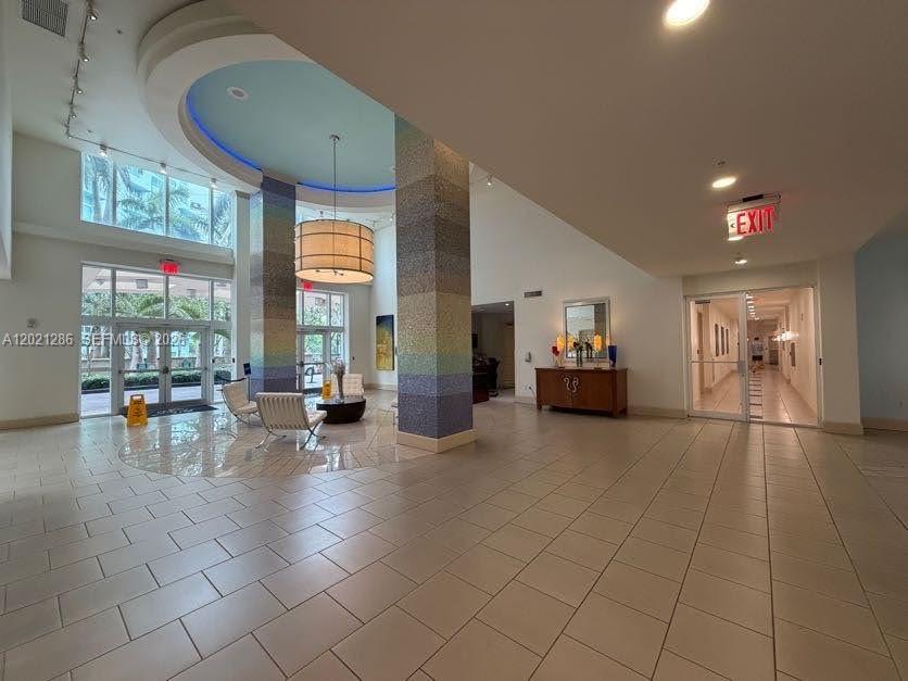 A spacious lobby features tiled floors, a decorative central pillar, and a large drum chandelier — 2000 N Bayshore Dr # 126, Miami FL 33137, MIAMI, FL