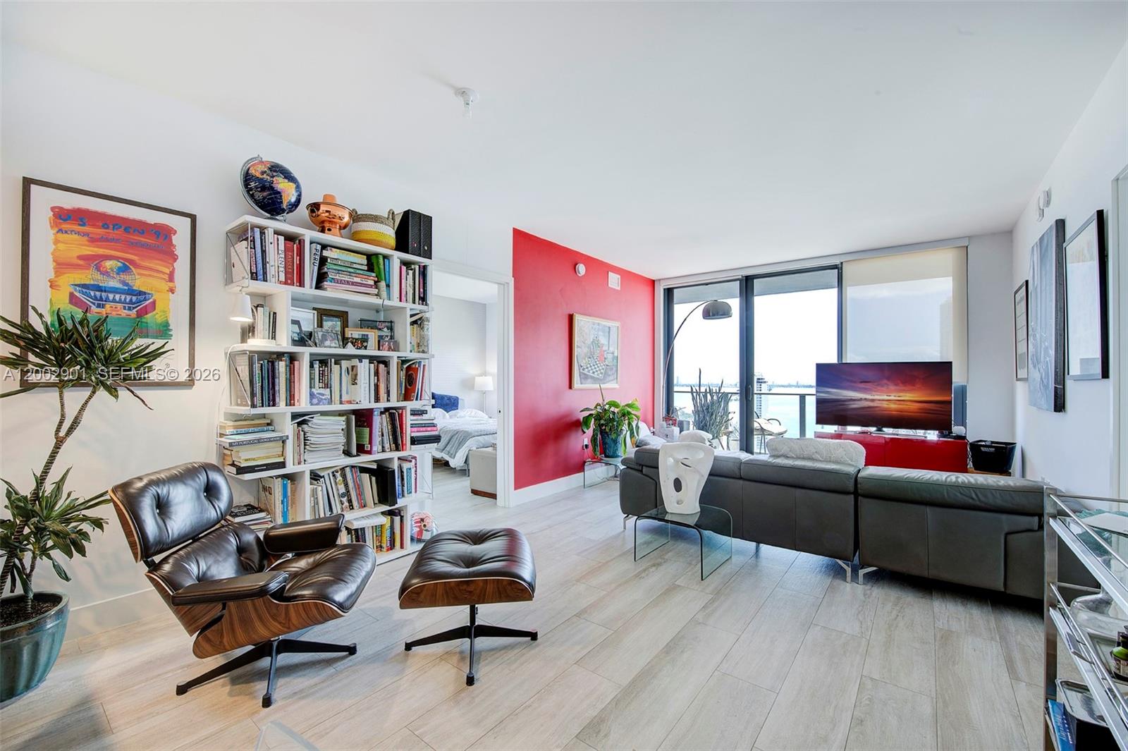 A living room features a red accent wall, a bookshelf, and a leather lounge chair — 121 NE 34th St # 1607, Miami FL 33137, MIAMI, FL
