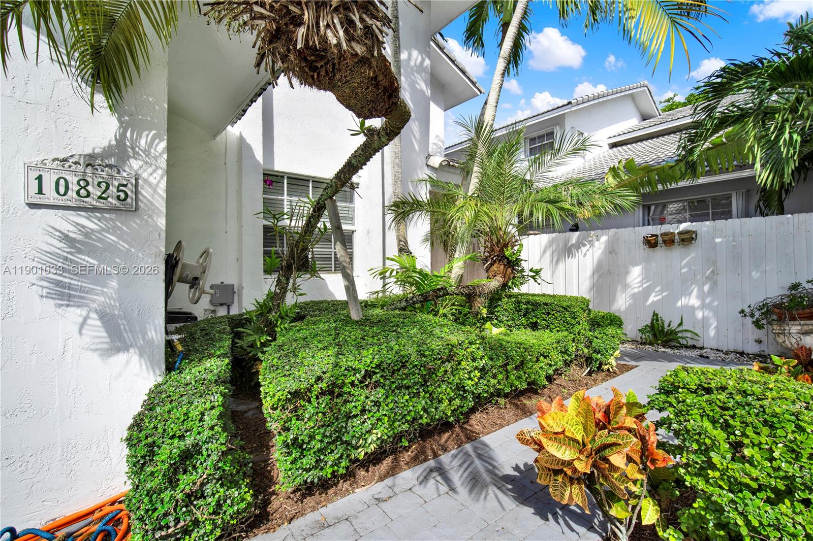 A white house exterior features a landscaped garden, a paved walkway, and a palm tree — 10825 SW 91st Ln, Miami FL 33176, MIAMI, FL