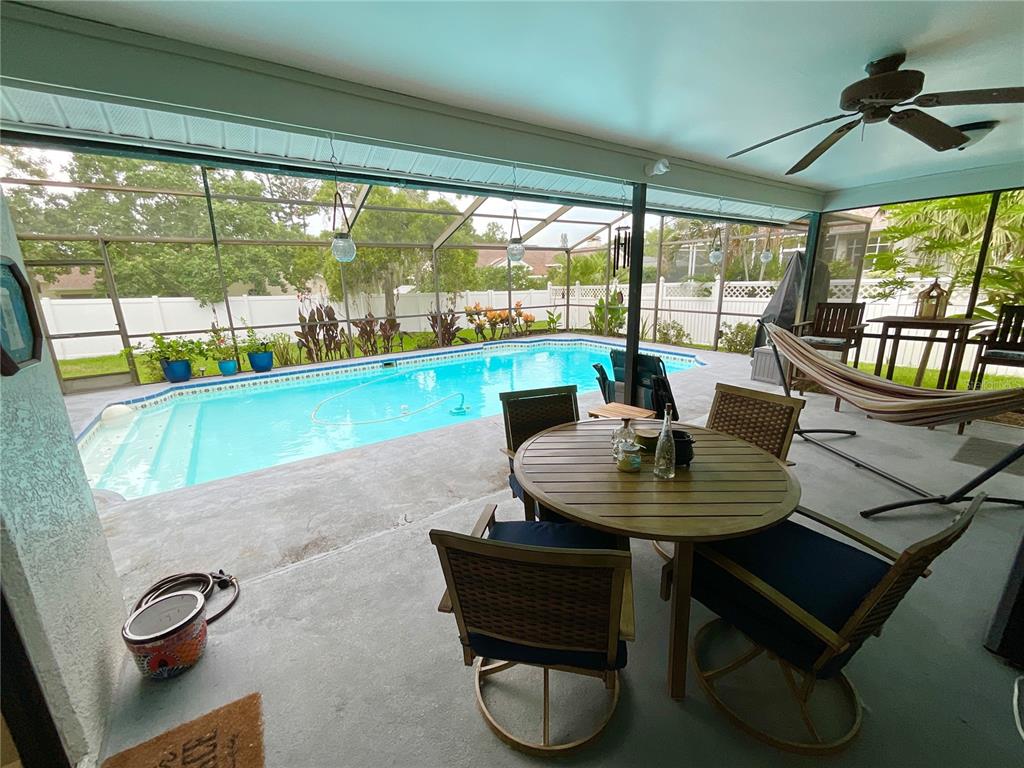 A covered patio features a dining set, a hammock, and a screened-in swimming pool — 1349 HILLSIDE DRIVE, TARPON SPRINGS, FL
