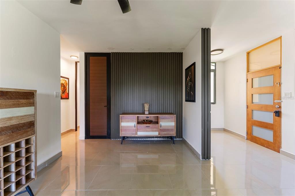 A wooden media console sits against a stone accent wall beneath a circular wooden art piece — 3104 EL DORADO CLUB UNIT 3104, VEGA ALTA, PR