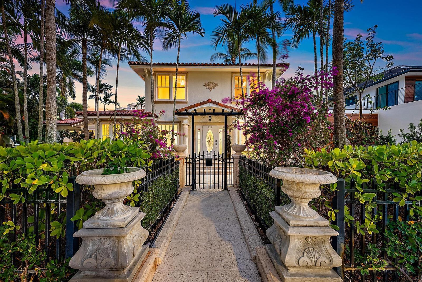 A two-story Mediterranean-style house features a gated walkway, stone urns, and lush tropical landscaping — 228 9th Street, West Palm Beach FL 33401, WEST PALM BEACH, FL