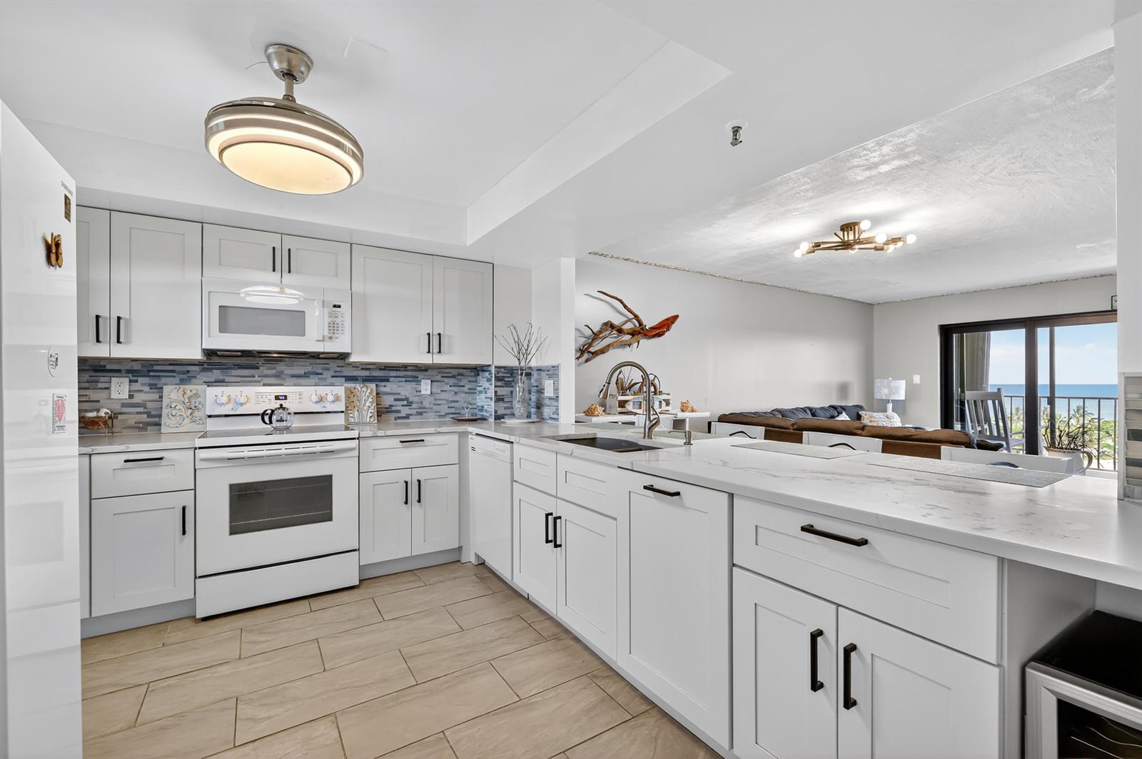 A modern kitchen with white cabinets, quartz countertops, and a view of the ocean — 801 S Ocean Drive # 910, Fort Pierce FL 34949, FORT PIERCE, FL