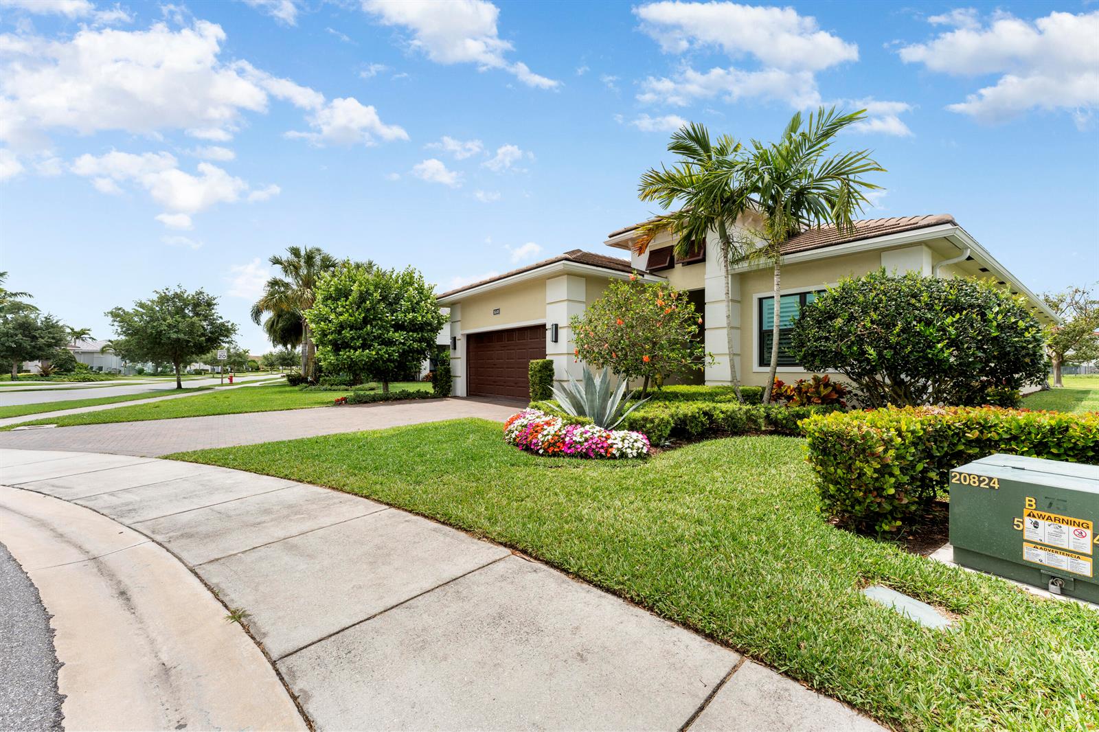A single-story house with a paved driveway, manicured lawn, and landscaping under a blue sky — 16148 Key Biscayne Lane, Westlake FL 33470, WESTLAKE, FL