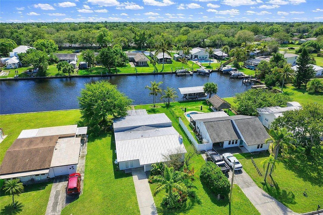 A white single-story house with a metal roof and illuminated walkway at sunset — 241 14th Place, Vero Beach FL 32960, VERO BEACH, FL