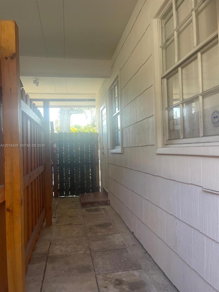 A narrow outdoor walkway features a wooden fence, a tiled floor, and a white wall — 3531 SW 13th St # A, Miami FL 33145, MIAMI, FL
