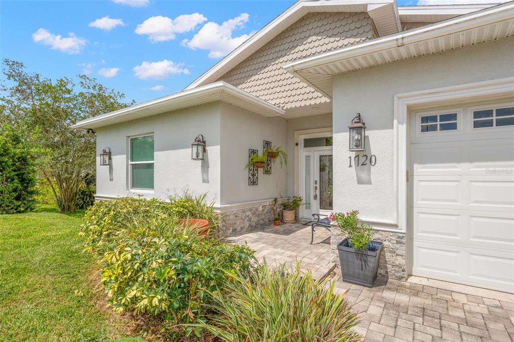 The exterior of a house features a paved entryway, a white garage door, and landscaping — 1720 VERDE DRIVE, CLEARWATER, FL