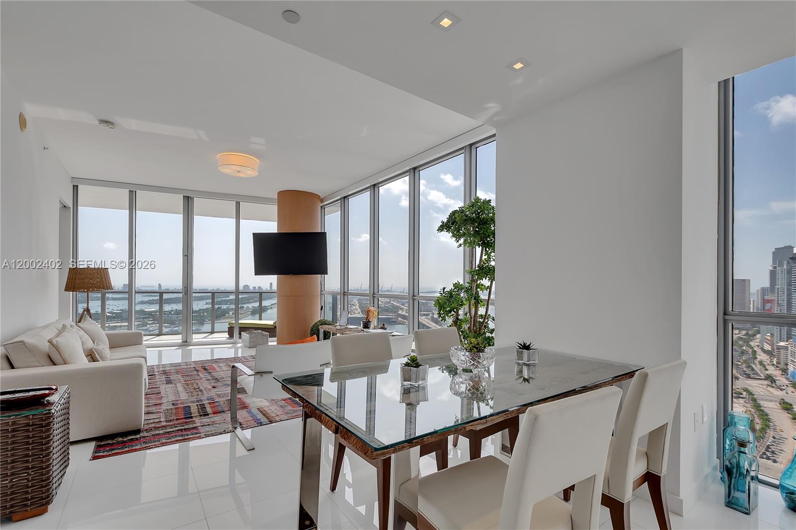 A modern living and dining area features floor-to-ceiling windows with expansive city and water views — 1100 Biscayne Blvd # 3901, Miami FL 33132, MIAMI, FL