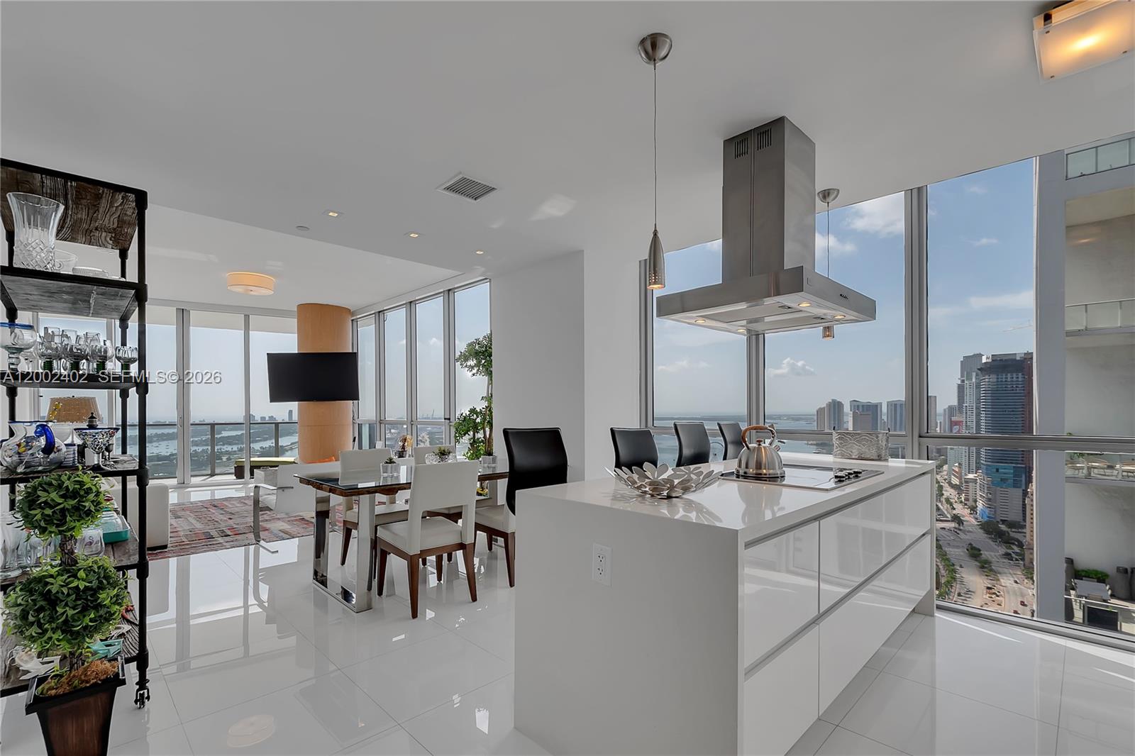 A modern kitchen and dining area feature white cabinetry, a central island, and floor-to-ceiling windows — 1100 Biscayne Blvd # 3901, Miami FL 33132, MIAMI, FL