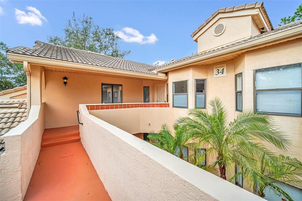 An exterior view of a multi-story apartment building with a walkway and palm trees — 7823 SUGAR BEND DRIVE UNIT 7823, ORLANDO, FL