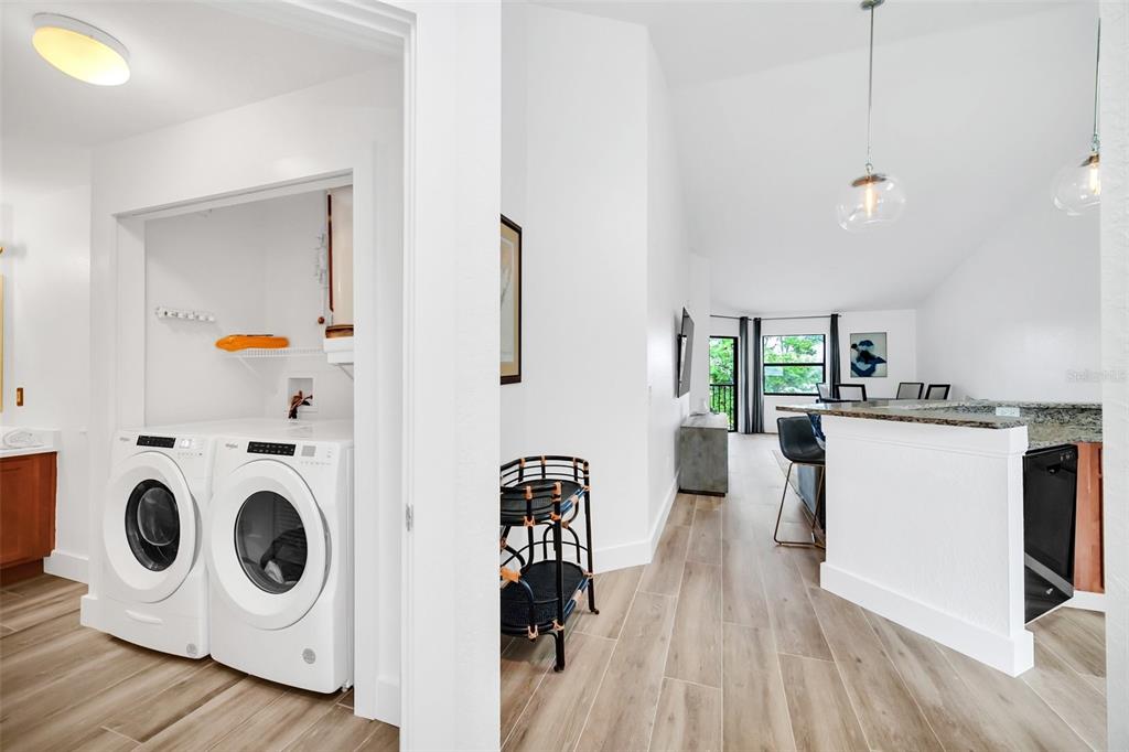 A laundry closet with white appliances sits beside a hallway leading to an open living area — 7823 SUGAR BEND DRIVE UNIT 7823, ORLANDO, FL