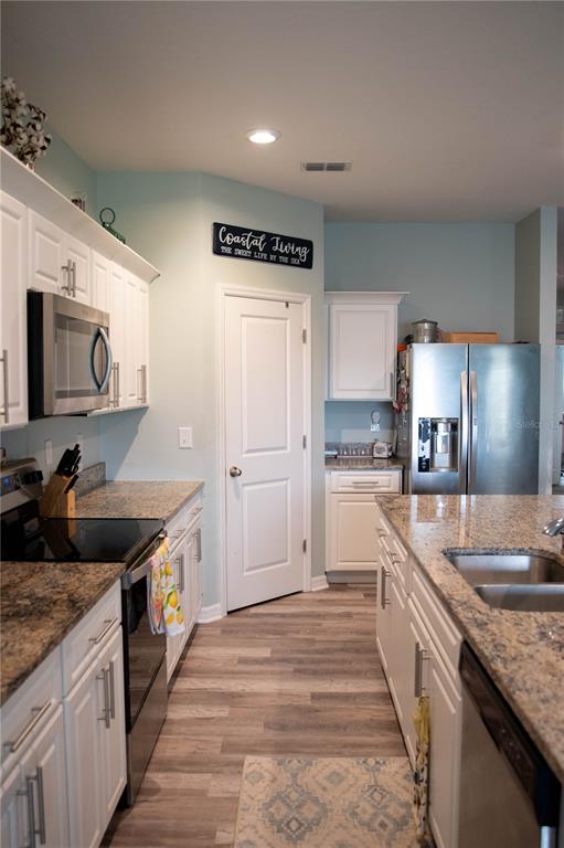 A kitchen features white cabinets, granite countertops, stainless steel appliances, and light blue walls — 3021 BLUE SHORES WAY, NEW SMYRNA BEACH, FL