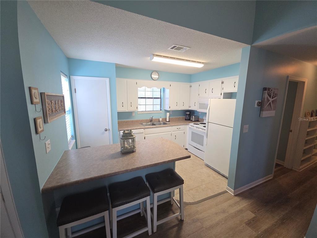 A kitchen with white cabinets, a breakfast bar, and light blue walls — 644 16TH STREET, PANAMA CITY BEACH, FL