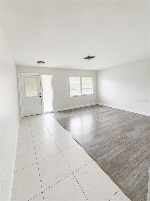 An interior room features a white tiled entryway transitioning into a wood-look laminate living area — 2428 LINWOOD DRIVE, SARASOTA, FL