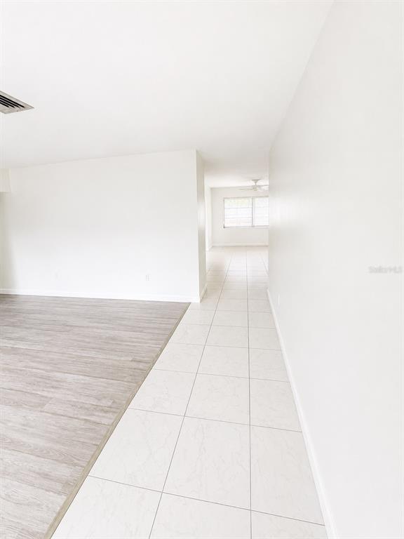 A hallway with white tile flooring leads to a room with a ceiling fan — 2428 LINWOOD DRIVE, SARASOTA, FL
