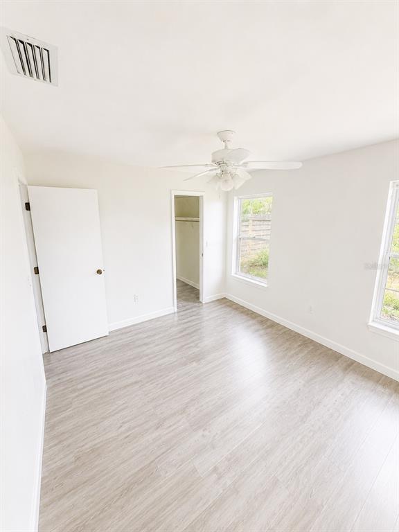 A bedroom with light-colored wood-look flooring, a ceiling fan, a closet, and two windows — 2428 LINWOOD DRIVE, SARASOTA, FL