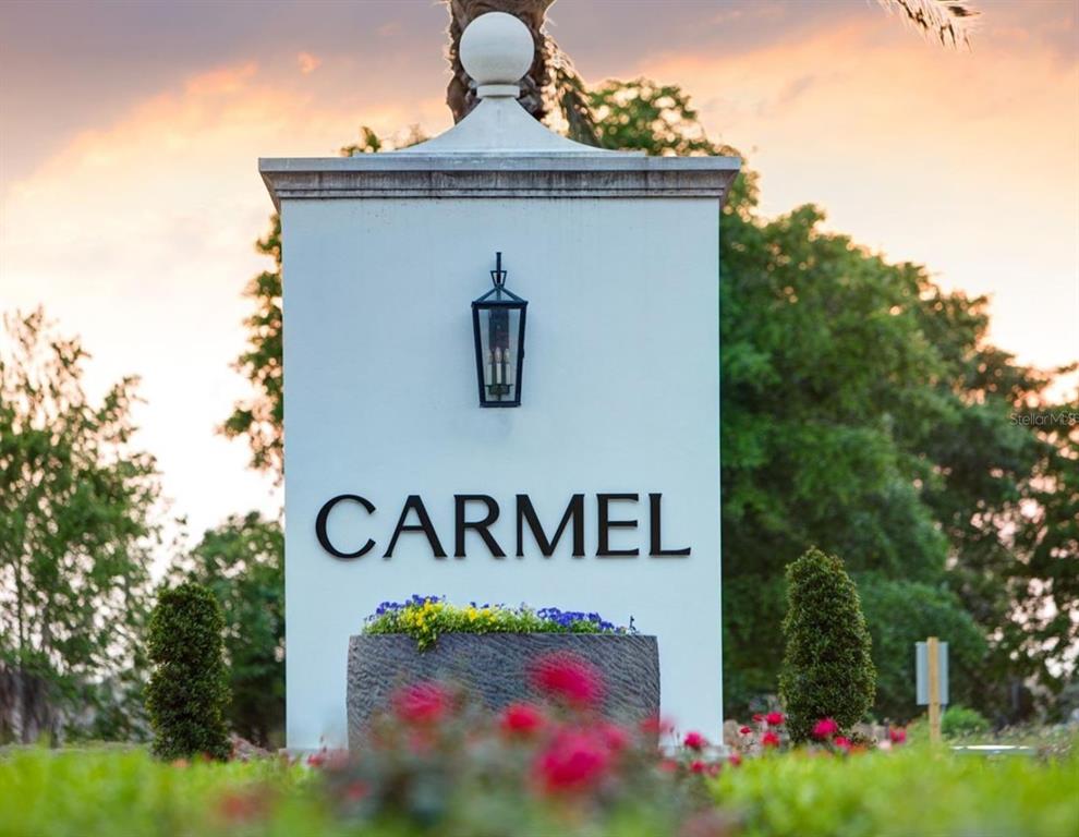 A white monument sign with the word Carmel stands in front of trees and flowers — 7011 VIA CARMEL WAY, ORLANDO, FL