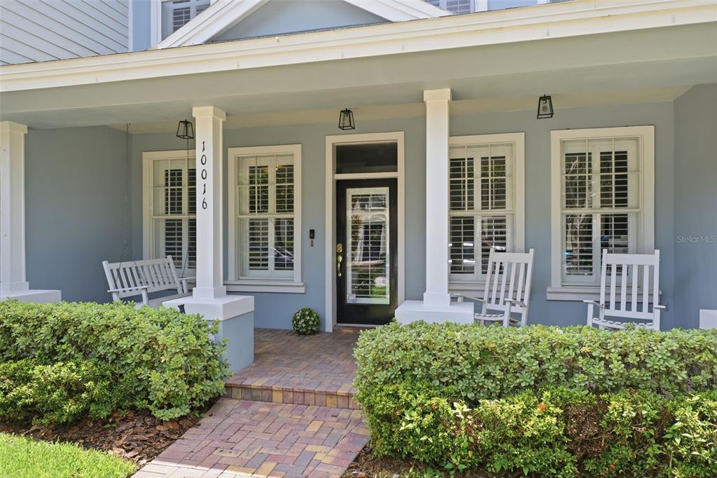 A front porch features a brick walkway, white columns, rocking chairs, and a blue exterior — 10016 BENTLEY WAY, TAMPA, FL