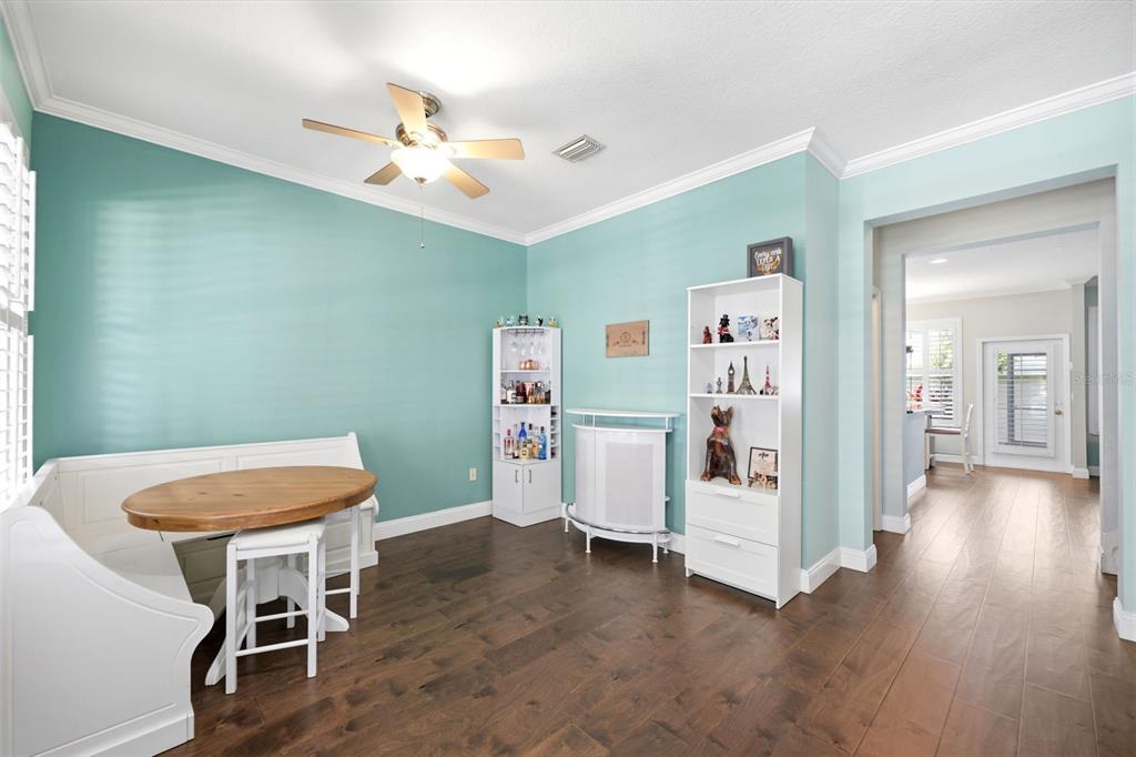 A dining area with teal walls, a white corner bench, a round table, and shelving units — 10016 BENTLEY WAY, TAMPA, FL