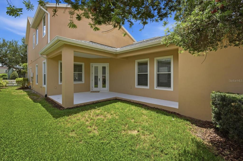 A tan two-story house features a covered concrete patio and a grassy backyard — 11310 WINTHROP LAKE DRIVE, RIVERVIEW, FL