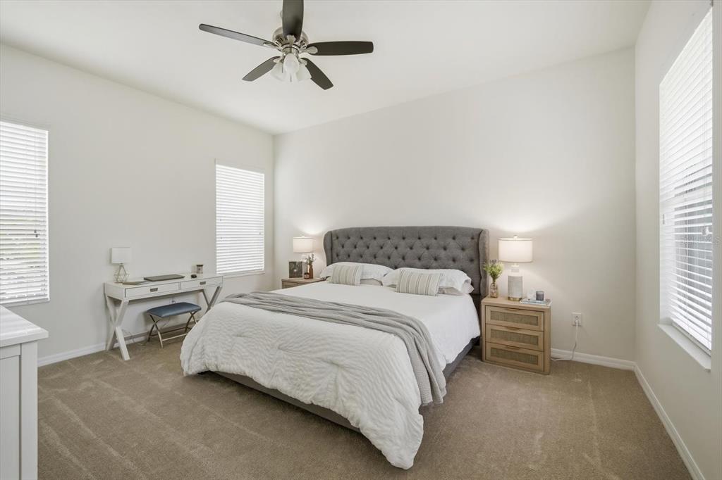 A bedroom features a tufted grey headboard, a white desk, and carpeted flooring — 11310 WINTHROP LAKE DRIVE, RIVERVIEW, FL