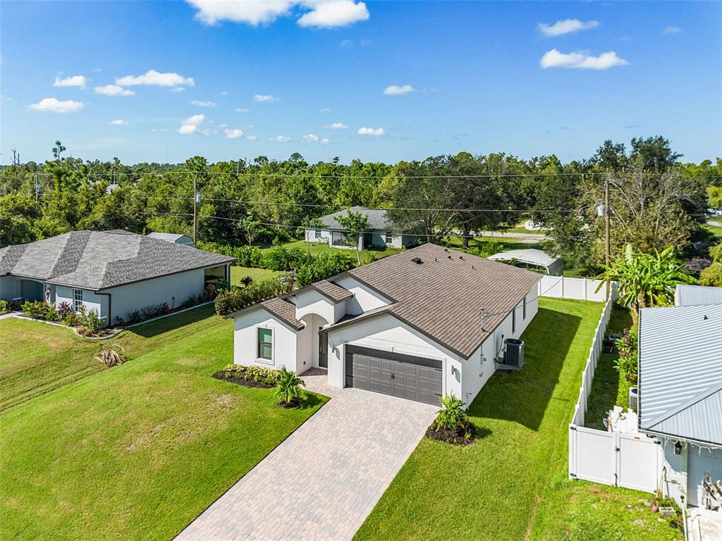 An aerial view shows a single-story house with a gray roof, white exterior, and paved driveway — 5413 DAYTON LANE, PORT CHARLOTTE, FL