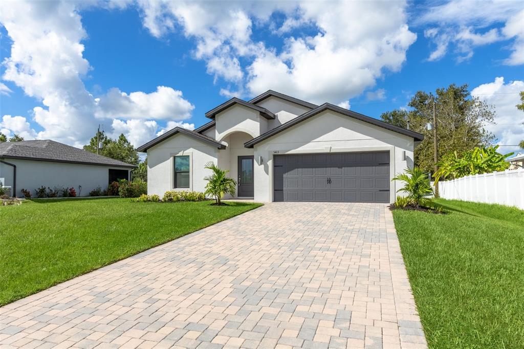 A single-story house with a paved driveway, a two-car garage, and a green lawn — 5413 DAYTON LANE, PORT CHARLOTTE, FL