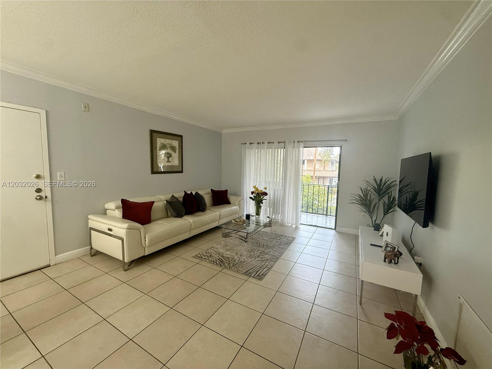 A living room features a white leather sofa, tile flooring, and a sliding glass door — 10413 N Kendall Dr # B208, Miami FL 33176, MIAMI, FL