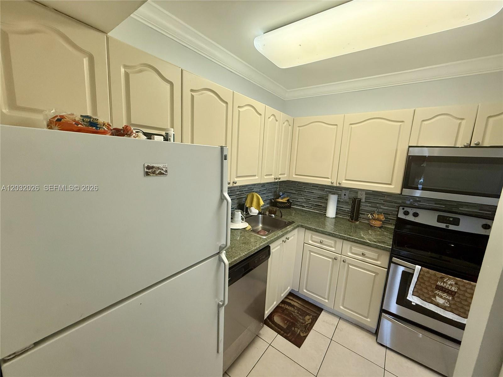 A kitchen features cream-colored cabinets, green countertops, stainless steel appliances, and a tiled floor — 10413 N Kendall Dr # B208, Miami FL 33176, MIAMI, FL