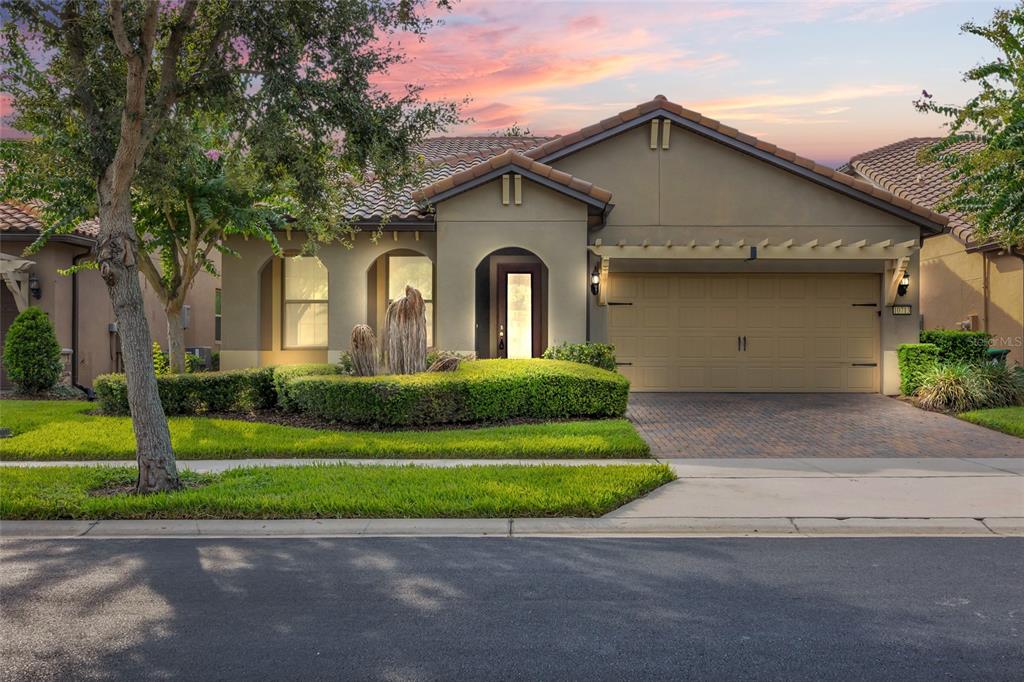 A single-story house with a tan stucco exterior, a tile roof, and a paved driveway — 10713 BERRY CREEK ROAD, ORLANDO, FL