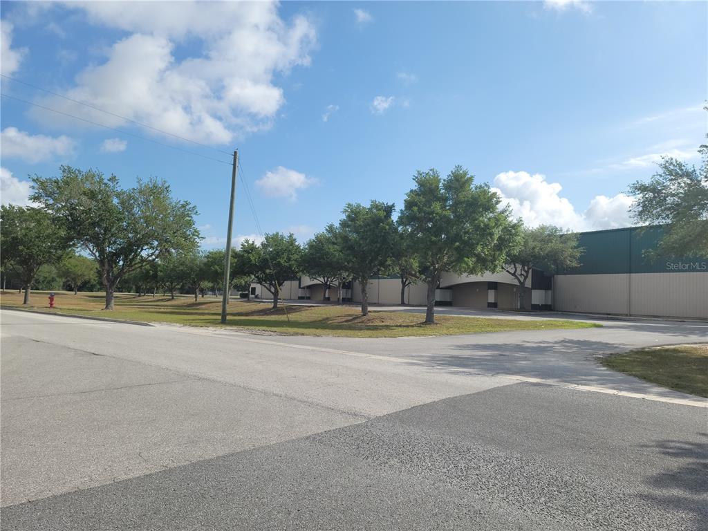 A low-rise commercial warehouse building sits behind a row of trees along a paved road — 1501 SW 44TH AVENUE, OCALA, FL