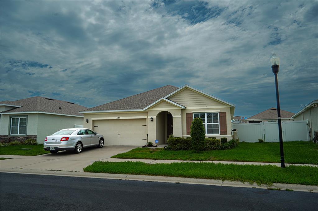 A single-story suburban house with a beige exterior, a two-car garage, and a driveway — 3184 ROYAL TERN DRIVE, WINTER HAVEN, FL
