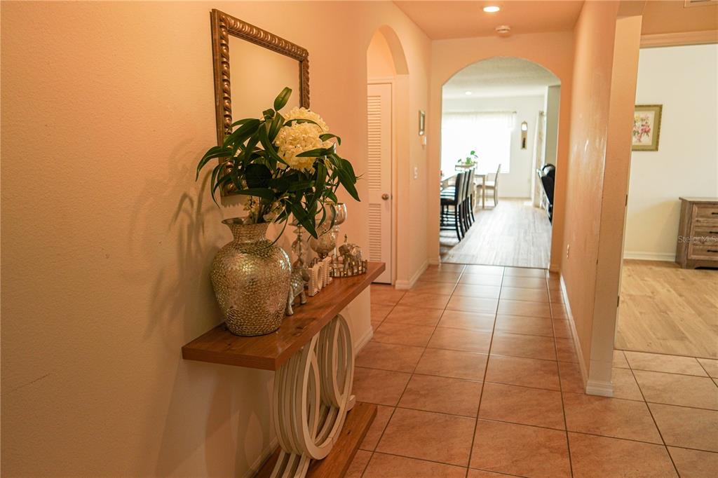 A hallway features a wooden console table with decor, tile flooring, and an arched entryway — 3184 ROYAL TERN DRIVE, WINTER HAVEN, FL