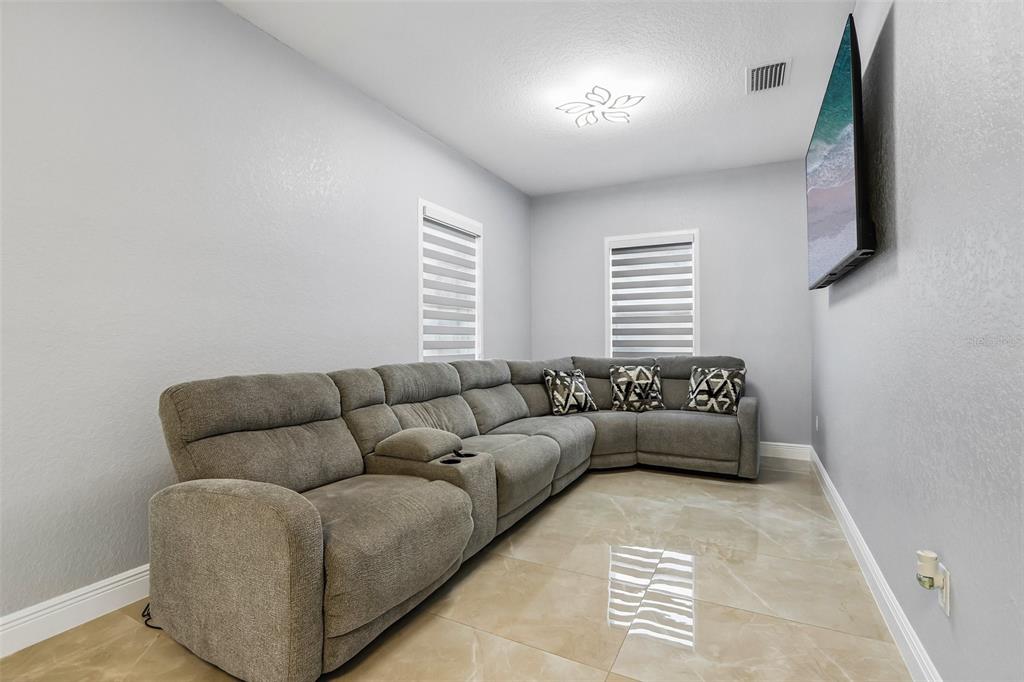 A living room features a large gray sectional sofa, tiled floors, and a wall-mounted television — 2703 AUBURN AVENUE W, TAMPA, FL
