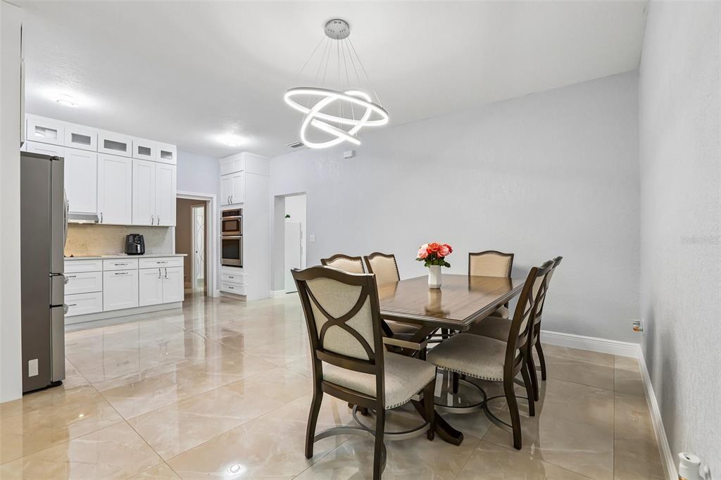 A dining area with a wooden table, six chairs, and a modern light fixture — 2703 AUBURN AVENUE W, TAMPA, FL
