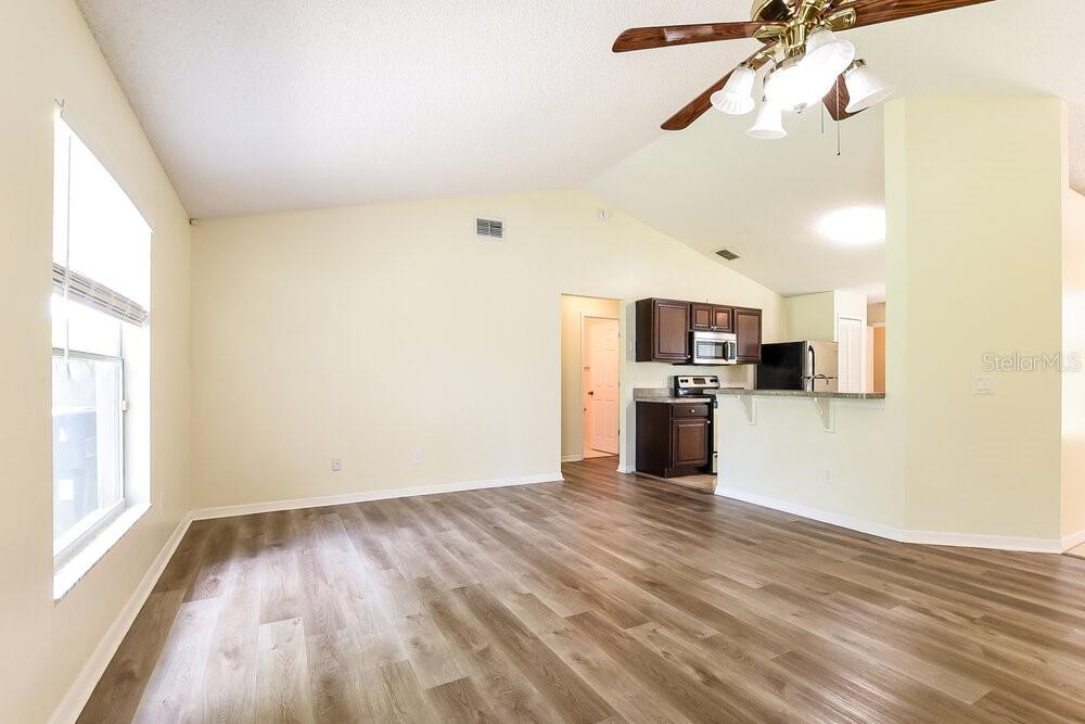 An open-concept living area features vaulted ceilings, light-colored walls, and wood-look vinyl plank flooring — 2556 COACHBRIDGE COURT, OVIEDO, FL