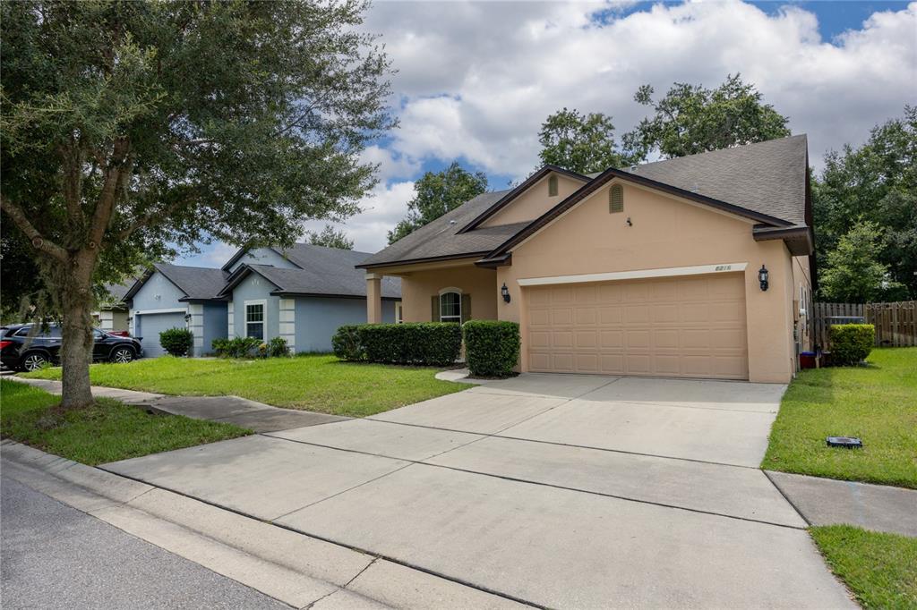 A tan, single-story suburban house with a two-car garage and a concrete driveway — 8216 NW 54TH STREET, GAINESVILLE, FL