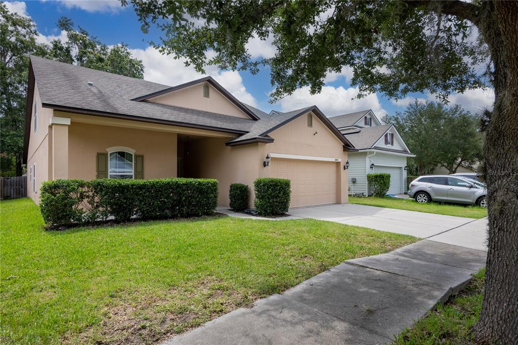 A single-story tan house with a two-car garage, a front lawn, and a paved driveway — 8216 NW 54TH STREET, GAINESVILLE, FL