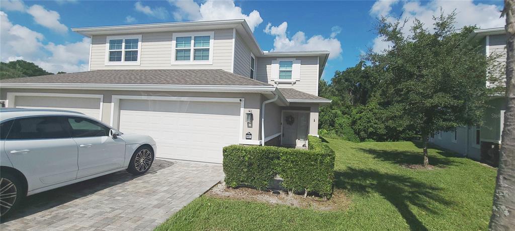 A paved patio sits outside a house with a screened-in porch and a large bush — 5330 RIVERWALK PRESERVE DRIVE, NEW PORT RICHEY, FL