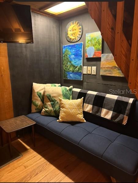 A blue futon sits against a dark wall decorated with paintings beneath a wooden staircase — 25235 142ND LANE NE UNIT 185, FORT MC COY, FL