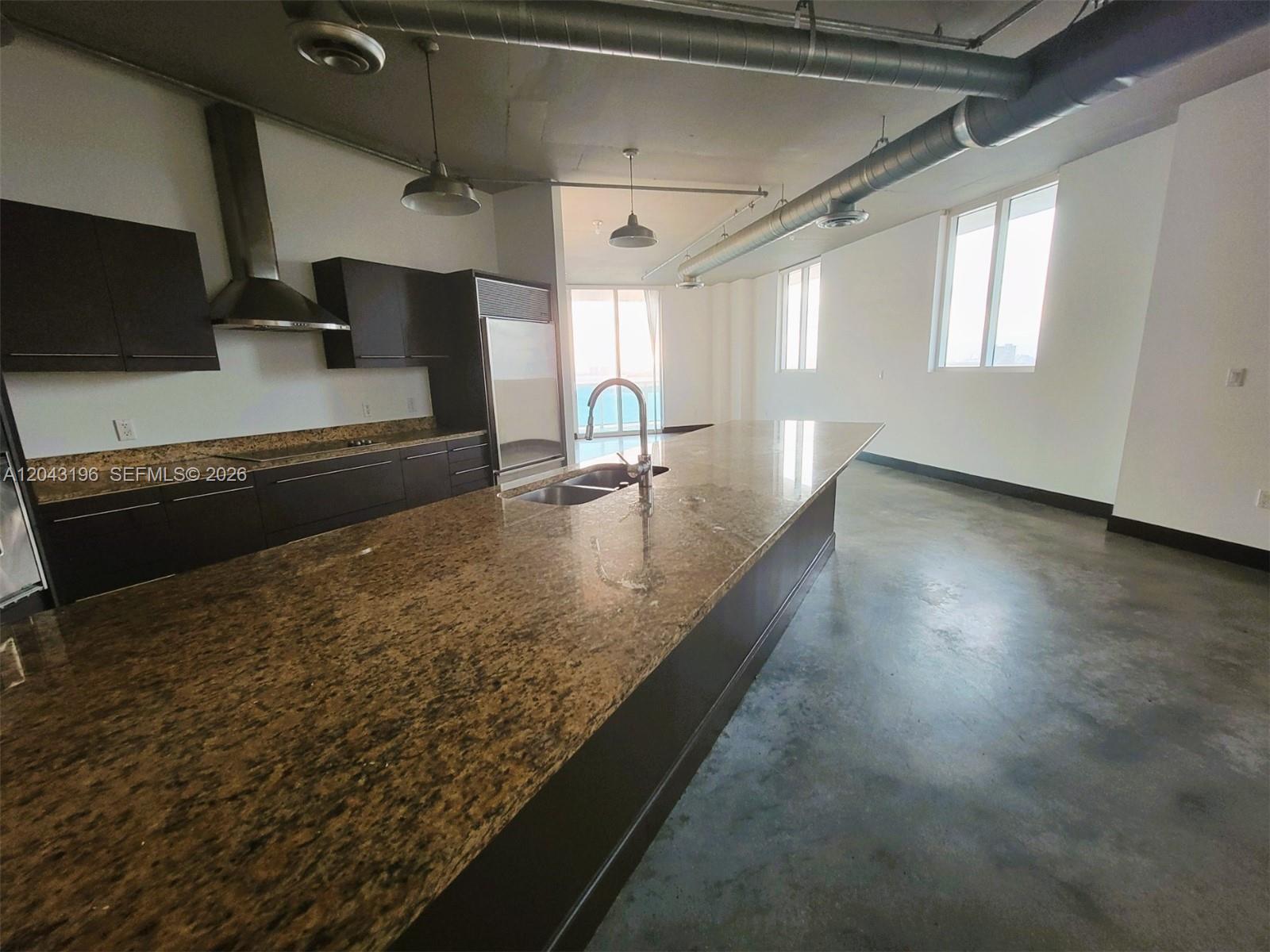 A modern kitchen features dark cabinets, granite countertops, and exposed industrial ductwork — 700 NE 25th St # 1004, Miami FL 33137, MIAMI, FL