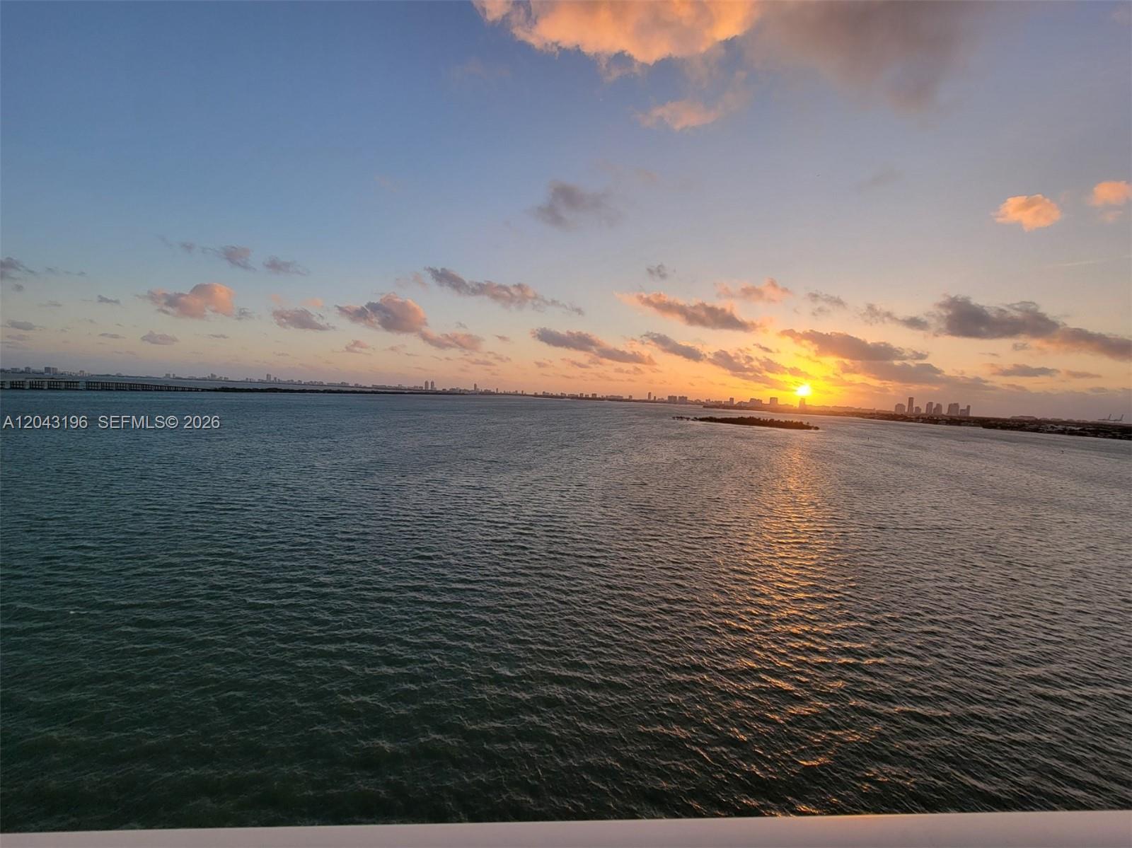 A wide-angle view of a sunset over a body of water with a distant city skyline — 700 NE 25th St # 1004, Miami FL 33137, MIAMI, FL