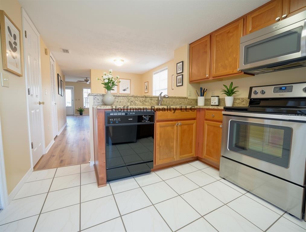 A kitchen with wood cabinets, stainless steel appliances, and white tile flooring — 2263 FLETCHERS POINT CIRCLE, TAMPA, FL